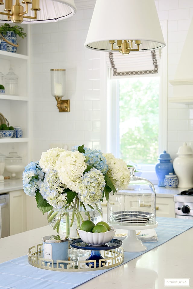 Beautiful blue and white hydrangeas for summer styled on a gold tray with a bowl of fresh limes.