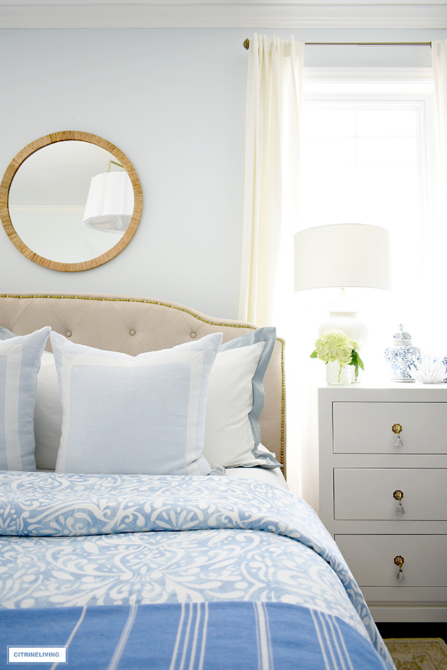 Gorgeous summer bedroom details with blue and white bedding, rattan mirror.
