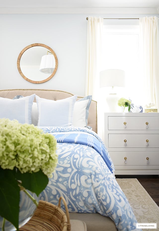 Gorgeous summer bedroom decorating, with light blue and white print bedding, fresh hydrangeas and rattan accents