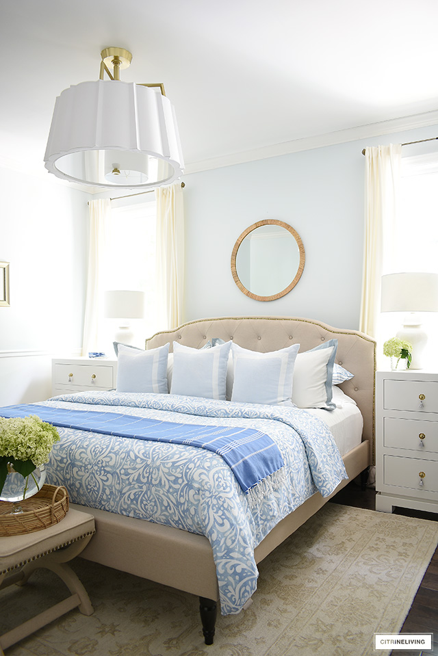 Chic summer bedroom decorating with light blue and white bedding, rattan accessories and fresh hydrangeas.