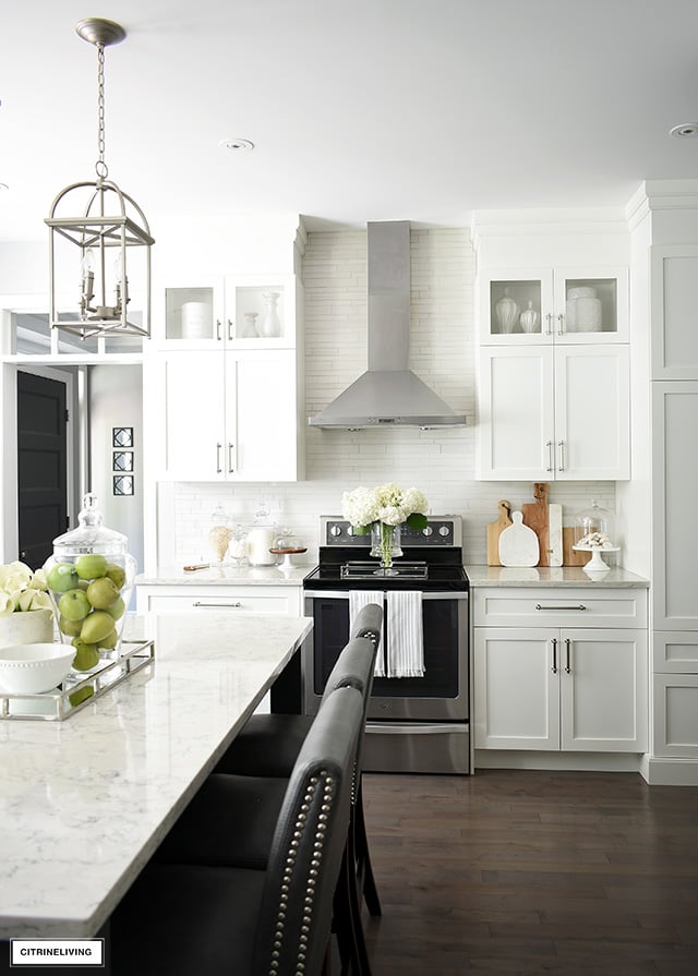 White kitchen with silver hardware, hardwood floors and grey island.