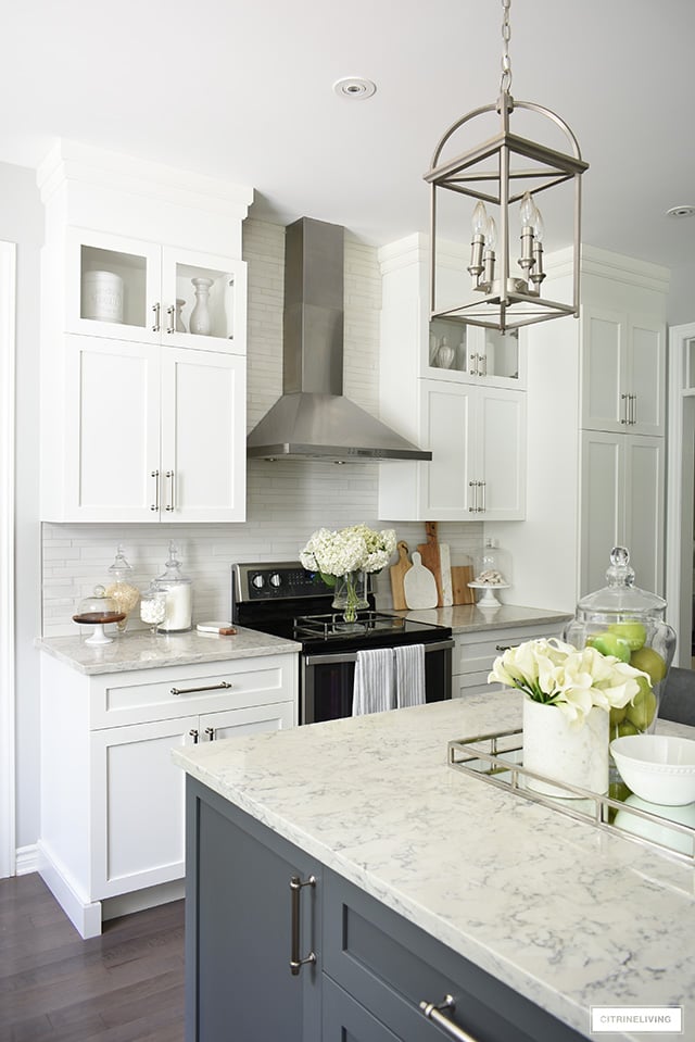 Gorgeous kitchen featuring white cabinets, grey island and brushed silver accents.