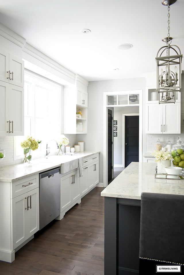 Beautiful classic white kitchen with brushed silver handles, white farm sink and hardwood floors.