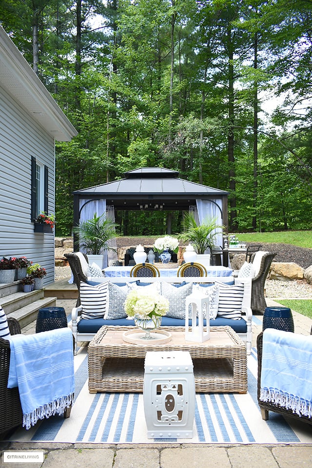 Gorgeous outdoor patio with blue and white decor, pillows, rugs and throws.