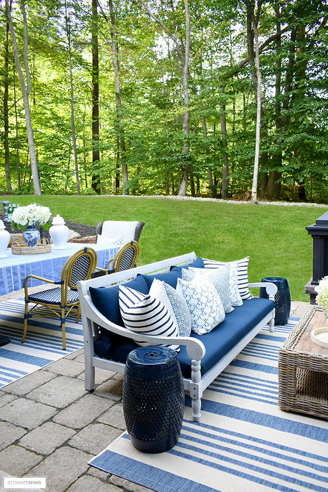 Beautiful outdoor patio with navy and white sofa filled with blue and white block-print pillows.