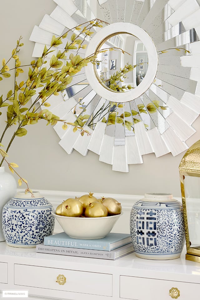 An elegant fall display with blue and white ginger jars, gold faux fruit and faux branches