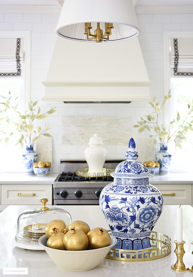 Blue and white ginger jar, gold pomegranates and an elegant cake stand styled together make a chic kitchen display.