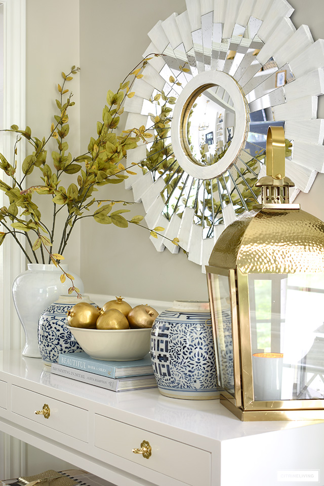 An elegant fall decorating vignette with beautiful ginger jars, faux fruit and branches, and gorgeous gold accents.