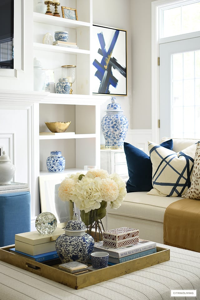 Living room decor for fall featuring beautiful blue and white accents, faux florals, throw pillows in rich colors.