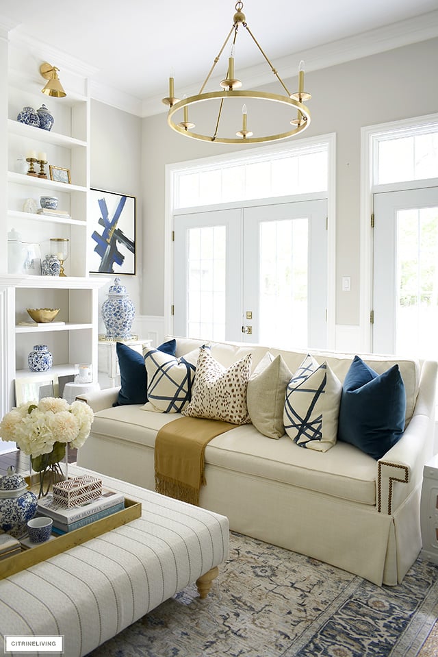 White sofa adorned with luxe throw pillows for fall, in rich navy, brown, cream and gold.