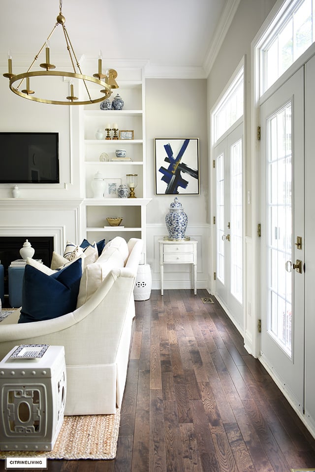 An open living room decorated for fall, french doors with transoms allow gorgeous natural light. Blue and white chinoiserie mixed with gold accents is sophisticated and elegant.