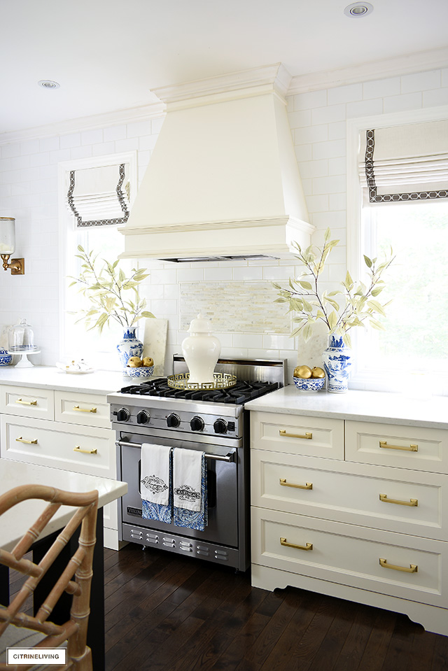White kitchen decorated for fall with blue and white chinoiserie, gold pomegranates and faux branches.