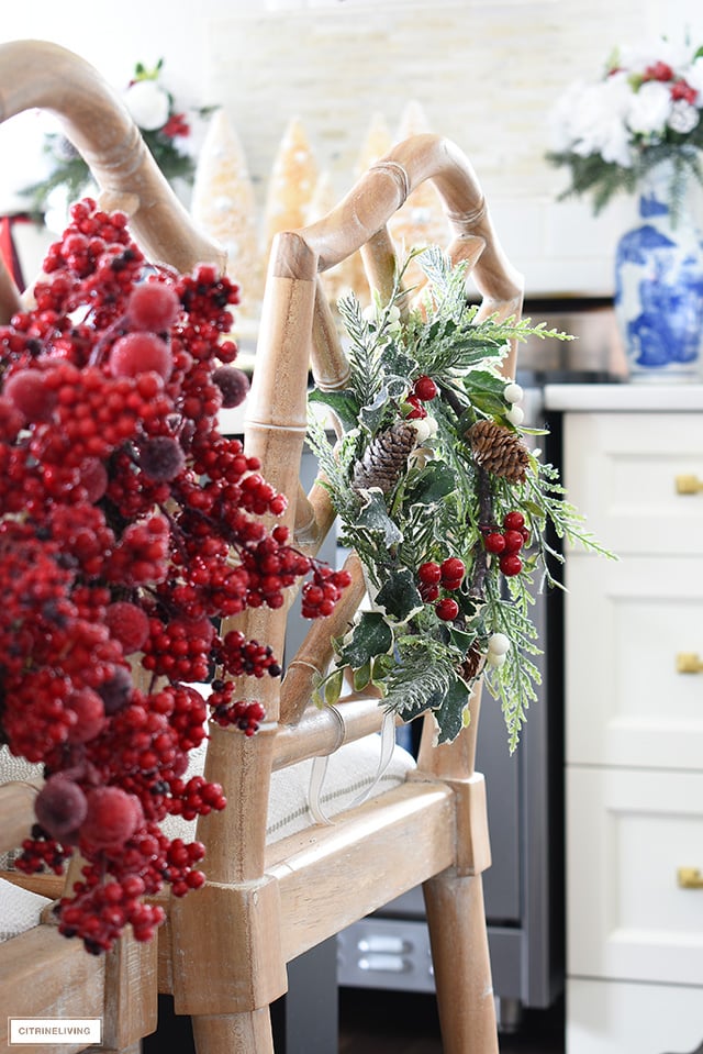 Dress up your kitchen barstools with a mix of different Christmas wreaths in greens and red frosted berries to add visual interest!