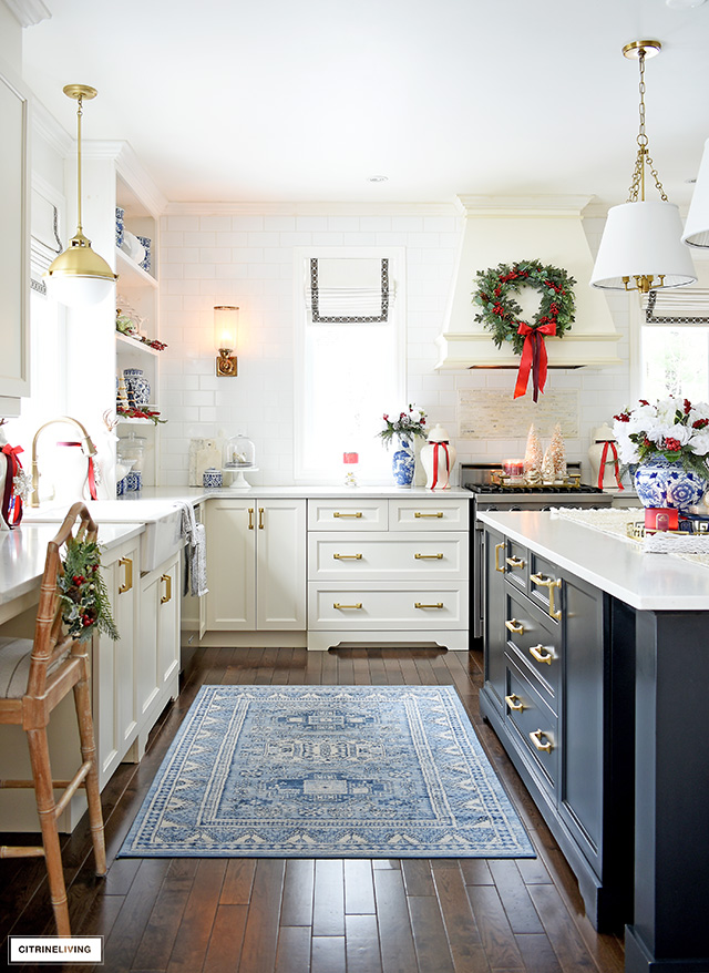 Gorgeous Christmas kitchen, decorated in blue and white with red accents, greenery and beautiful white flowers and red berries.