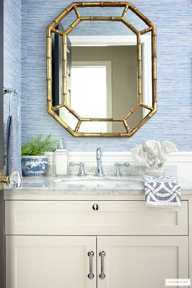 Blue grasscloth wallpaper and a white vanity adds coastal sophistication to a small bathroom.