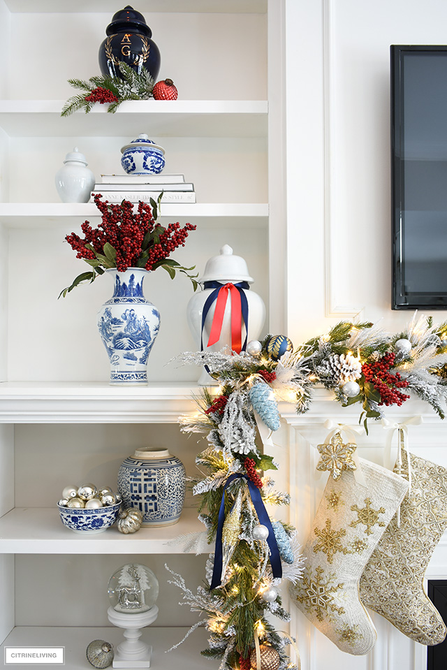 Bookshelves styled for Christmas with blue and white ginger jars and red berries.