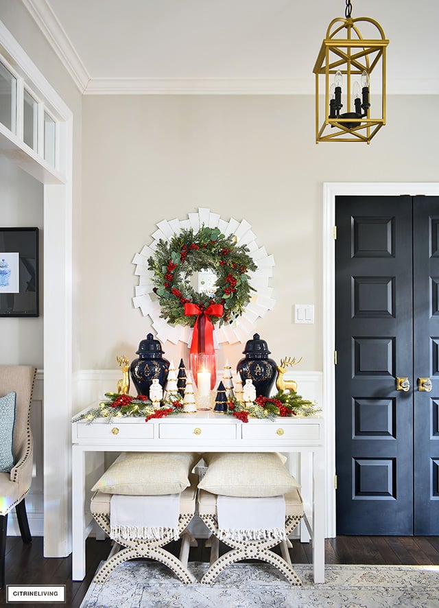 Sophisticated Christmas decorating - console table with ginger jars, holiday greenery, and a gorgeous lush wreath hung above.