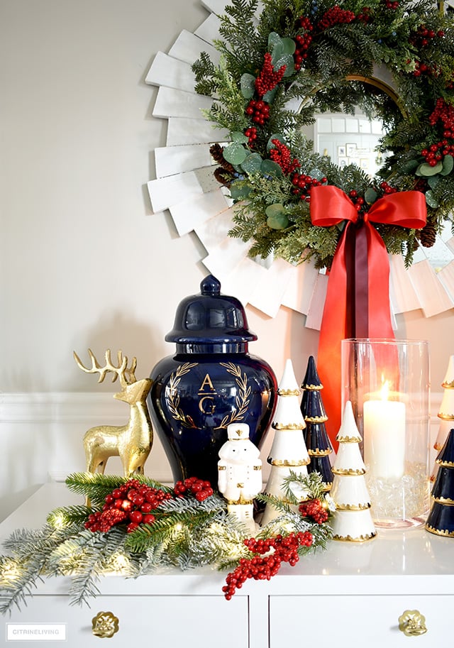 A beautiful Holiday display on a console table with a ginger jar, ceramic Christmas trees, nutcrackers and greenery.