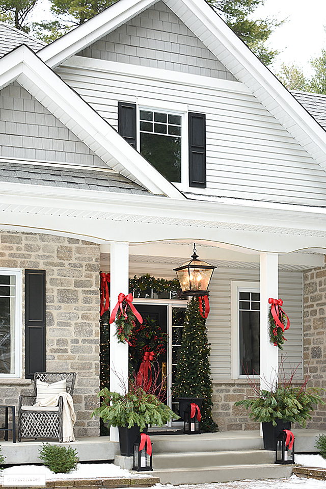 Beautiful Christmas porch decorated in classic red bows and greenery.