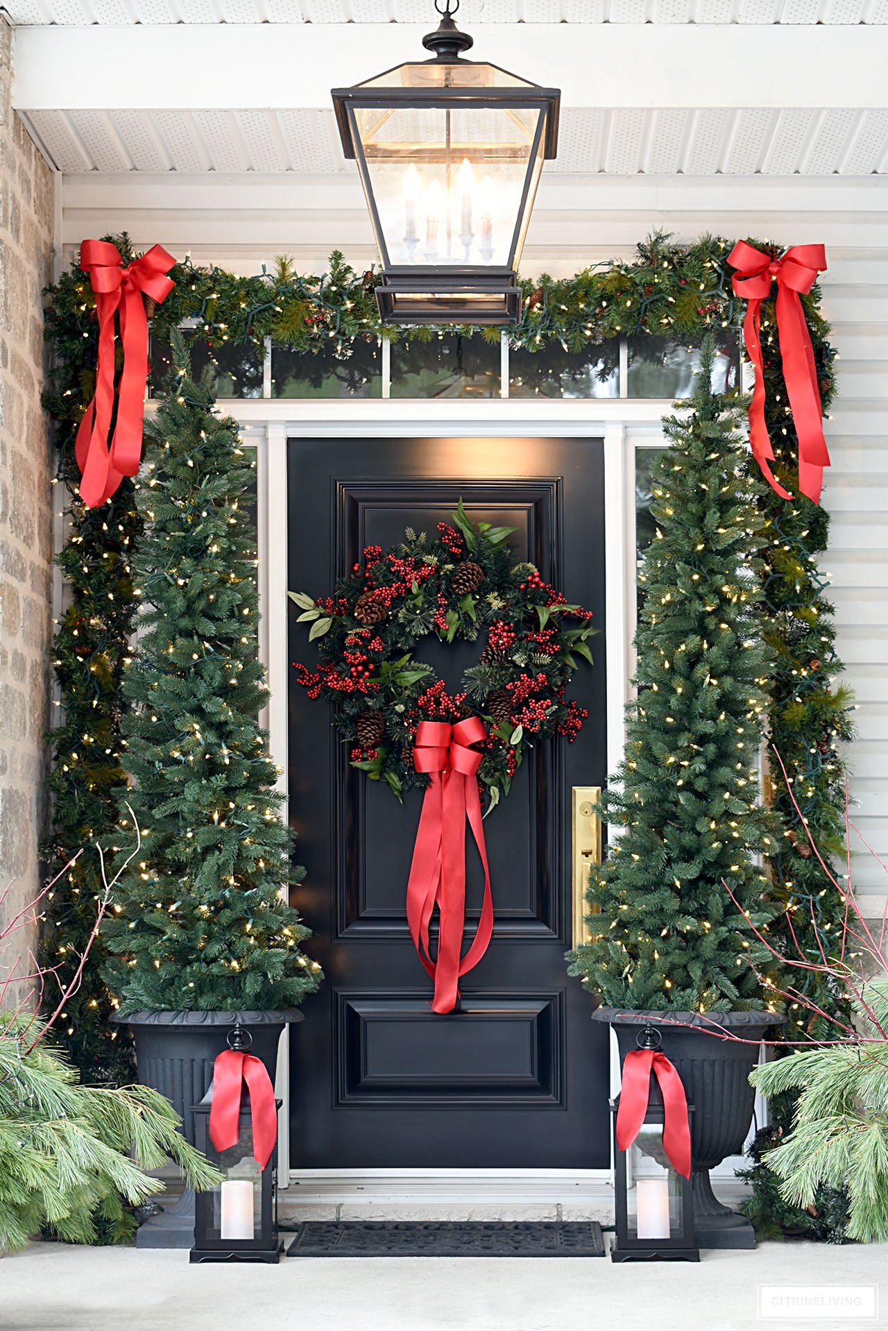 Elegant Christmas porch decorated in classic red bows and greenery.