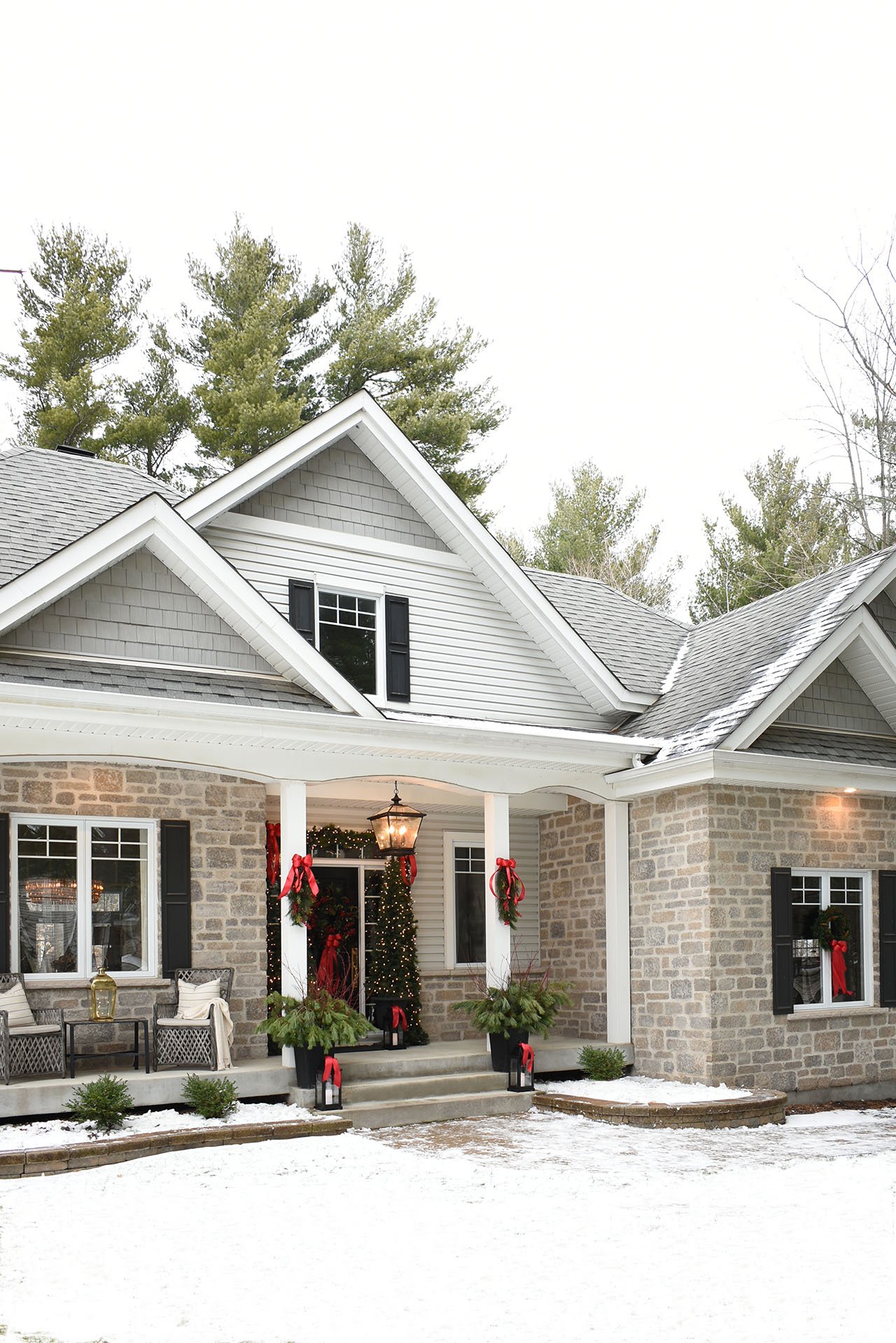 Christmas porch and home exterior dressed up in classic greenery and red bows.