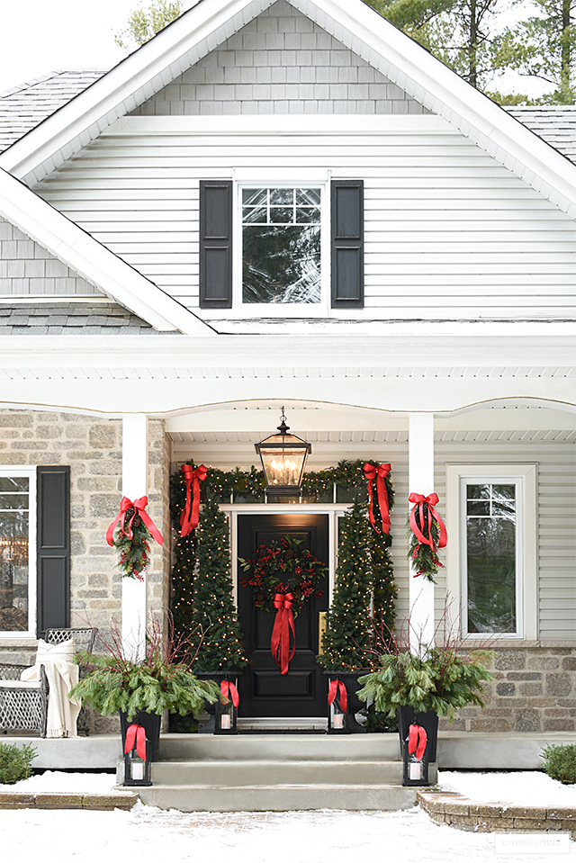 Classic holiday decorated porch is sophisticated and elegant with beautiful greenery and red bows.