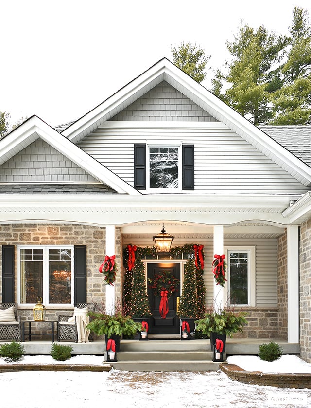 Christmas front porch decorated in classic greenery and red bows.