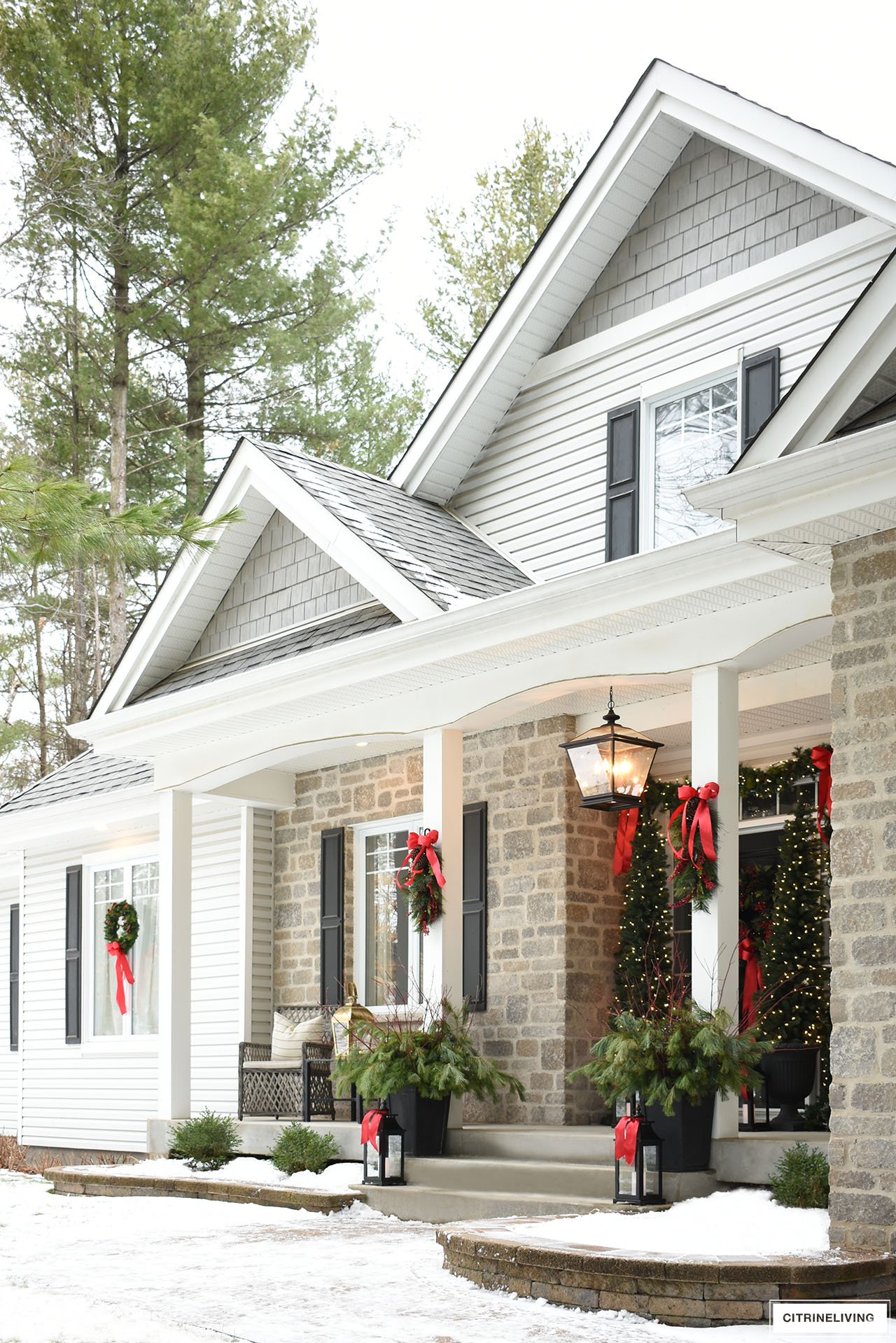 Sophisticated Christmas porch decor dressed in gorgeous greenery and classic red bows.