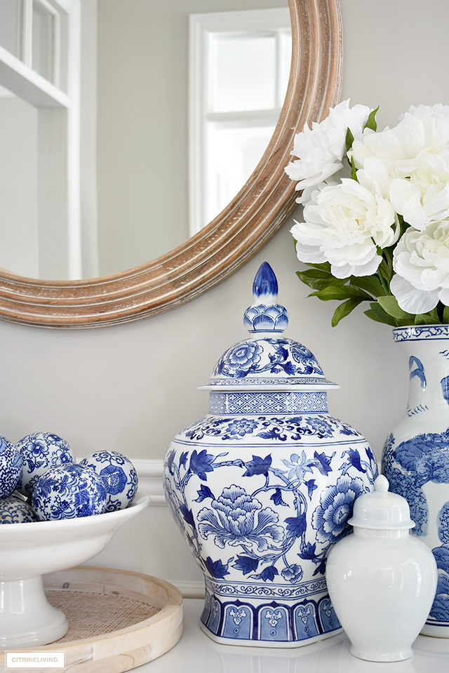 Blue and white ginger jar and vases with faux peonies styled on a white table.