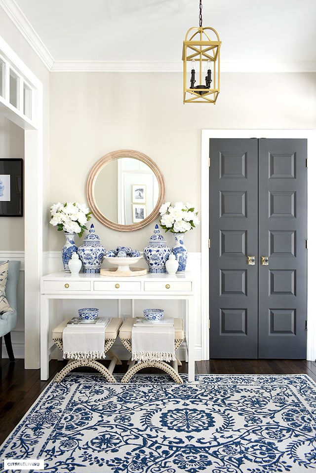 Elegant entryway decor for spring with blue and white rug, ginger jars, peonies and wood touches.