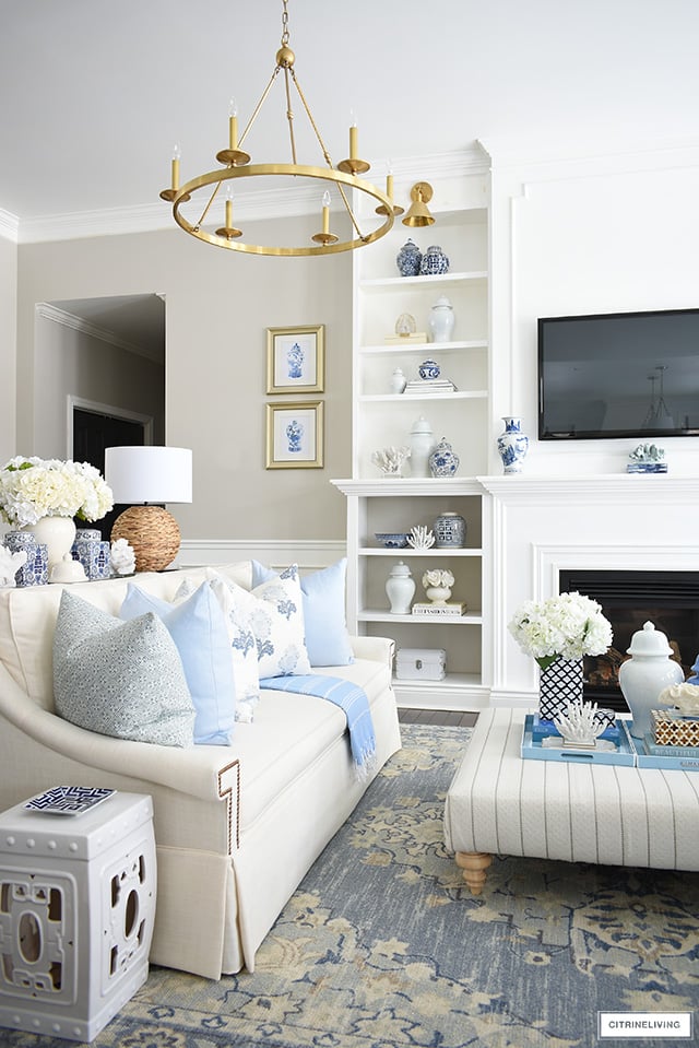 Spring living room decor with blue and white chinoiserie, light blue and cream pillows and accents, natural touches and faux florals.