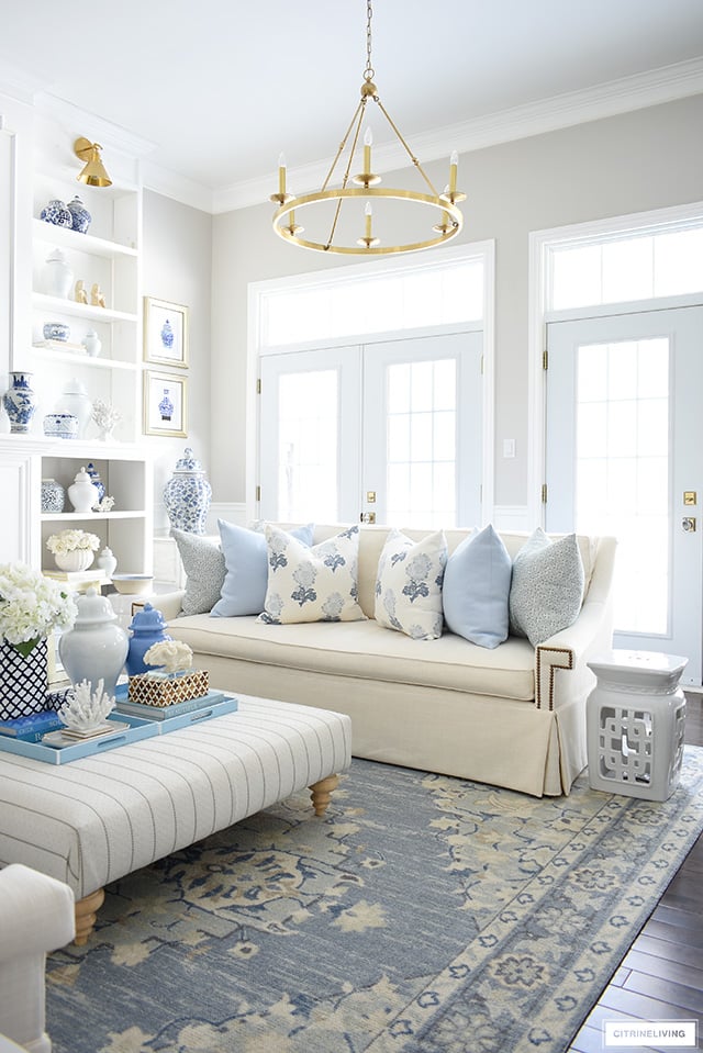 Spring living room decor in pretty blues, creamy whites, floral and geometric print pillows and chinoiserie touches.