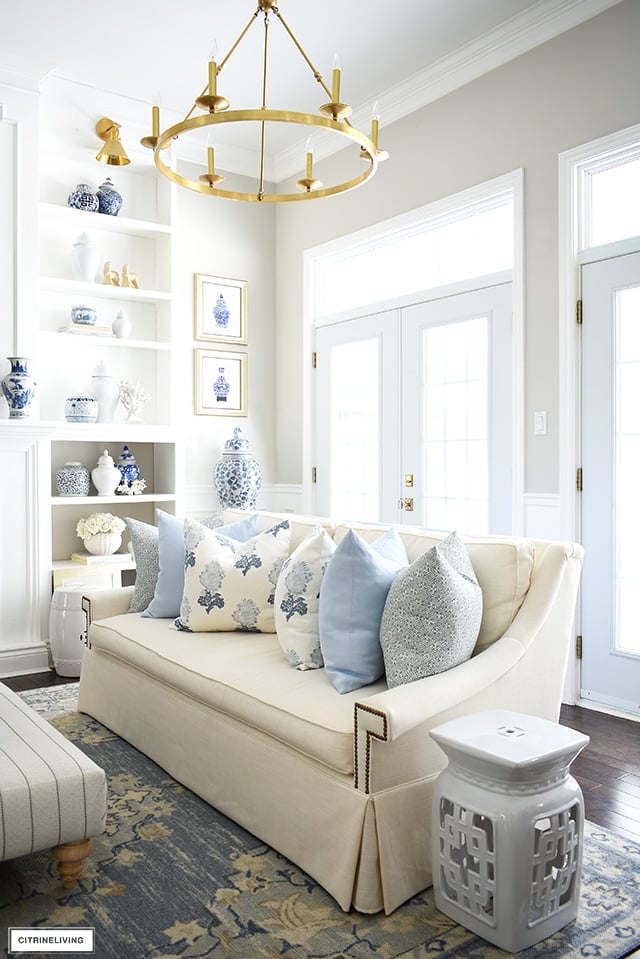 Spring living room decor with gorgeous soft blues, creamy whites, floral and geometric pillows, a light blue rug, and blue and white chinoiserie.