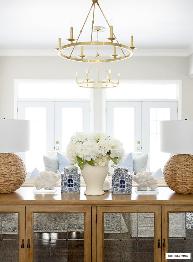 Spring living room decor with woven lamps, blue and white ginger jars, coral accents.