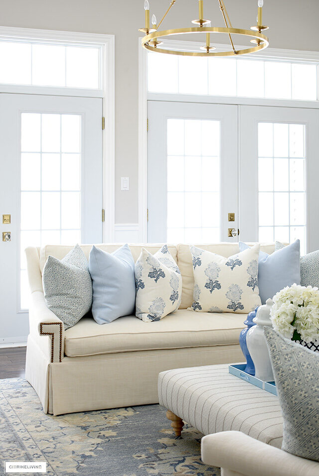 A gorgeous spring decorated living room with elegant soft blue and white throw pillows and a soft blue and beige rug.