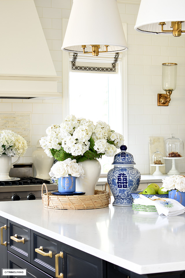 Kitchen island decorated with ginger jars, faux roses and geraniums.