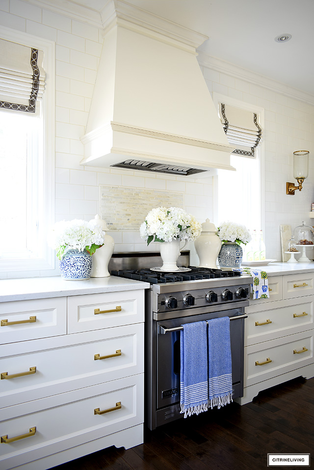 Kitchen range hood decorated for spring with blue and white ginger jars and faux florals.