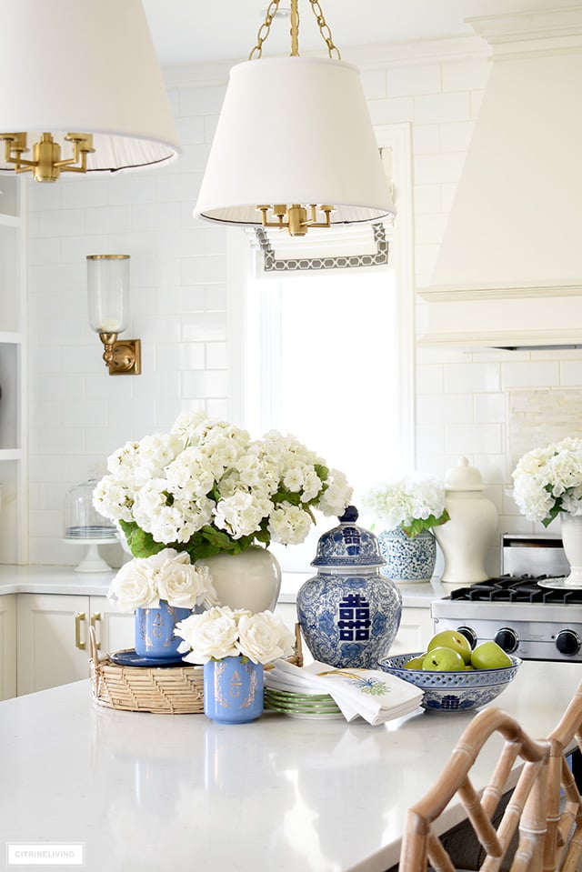 Kitchen decorated for spring with gorgeous blue and white accents, faux flowers, pretty dishes and green apples.