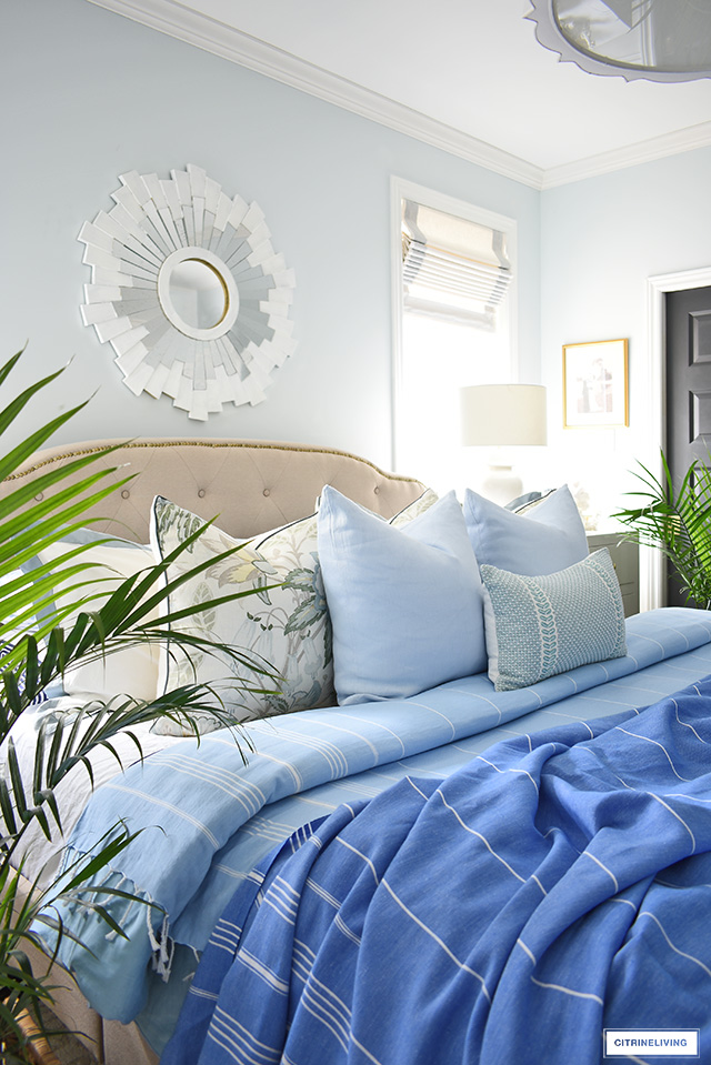 Beautifully layered bed for summer with striped blankets and throw pillows in blue and green.