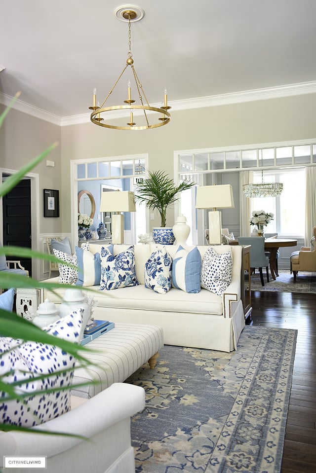 A gorgeous living room styled for summer with blue and white florals, stripes and animal print pillows.