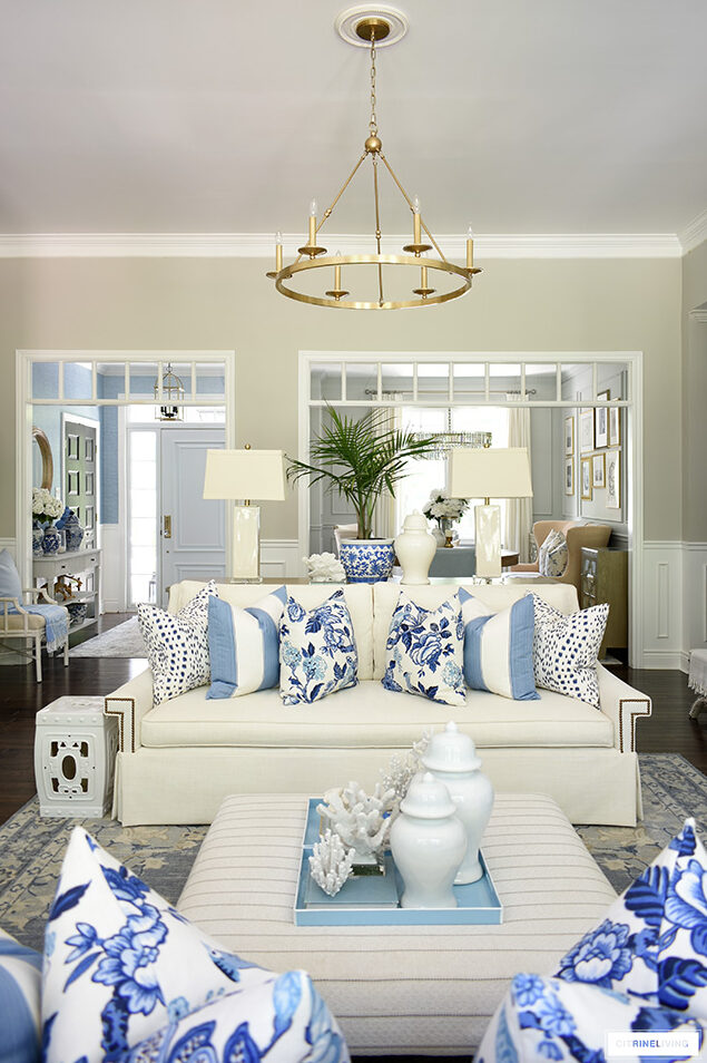 Gorgeous summer living room decorated with blue and white pillows, coral accents and palms.
