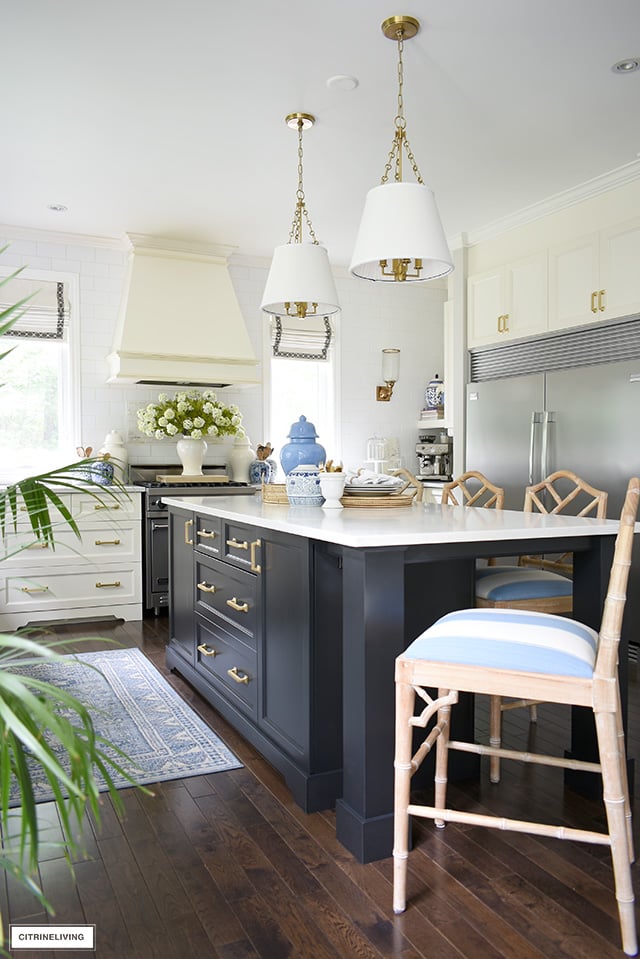 White kitchen with black island, styled for summer with blue and white accents and faux florals.