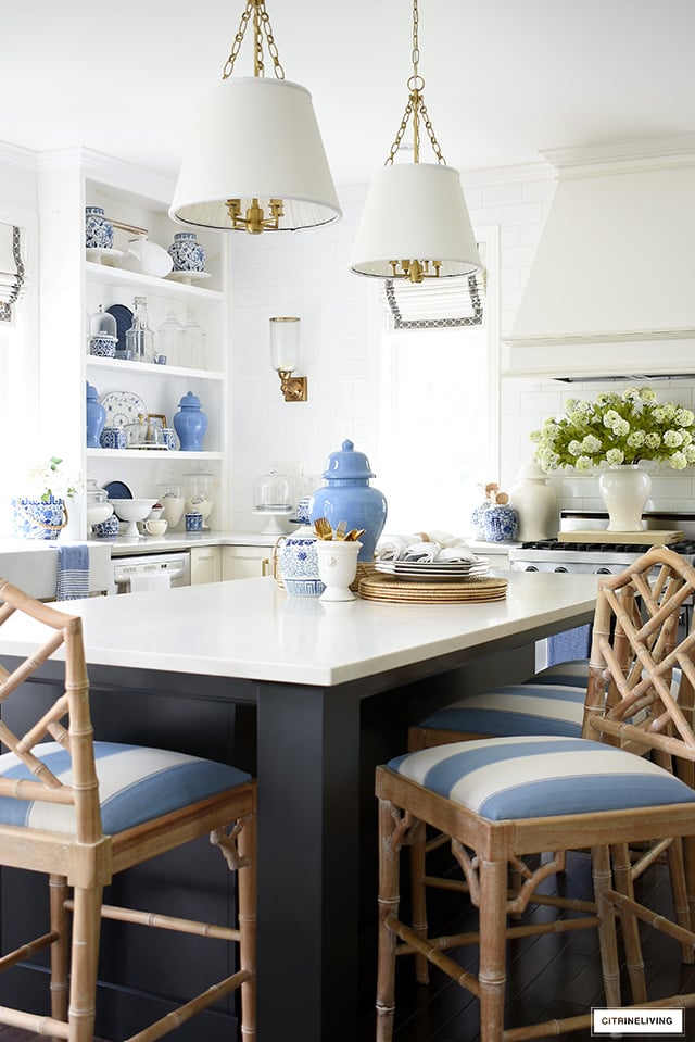 A gorgeous kitchen view of open shelves and island decorated for summer with chic blue and white accents.