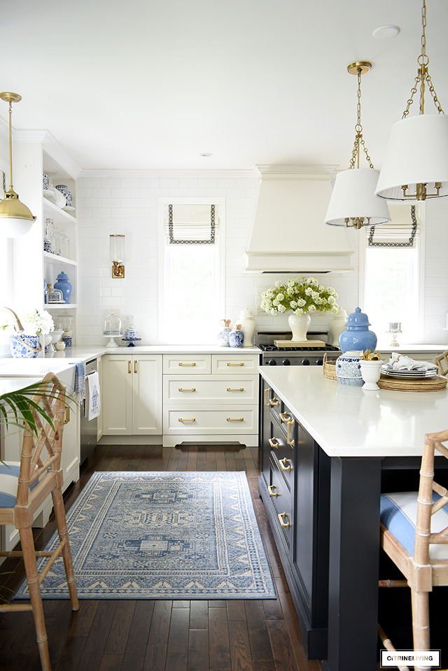 Elegantly classic kitchen styled with blue and white for summer - a blue rug, blue and white ginger jars and faux florals.