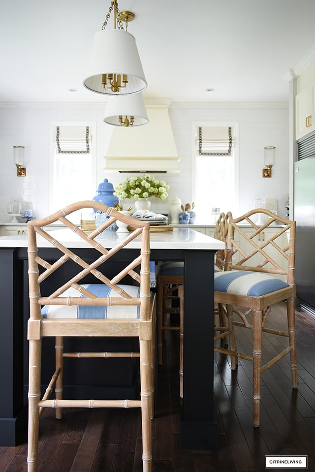 Kitchen island featuring chinoiserie chic bar stools covered in a blue and white striped fabric.