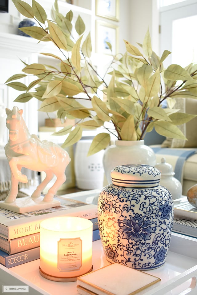 Scented candle, ginger jar, faux leaves and seasonal accessories styled on a tray for fall.