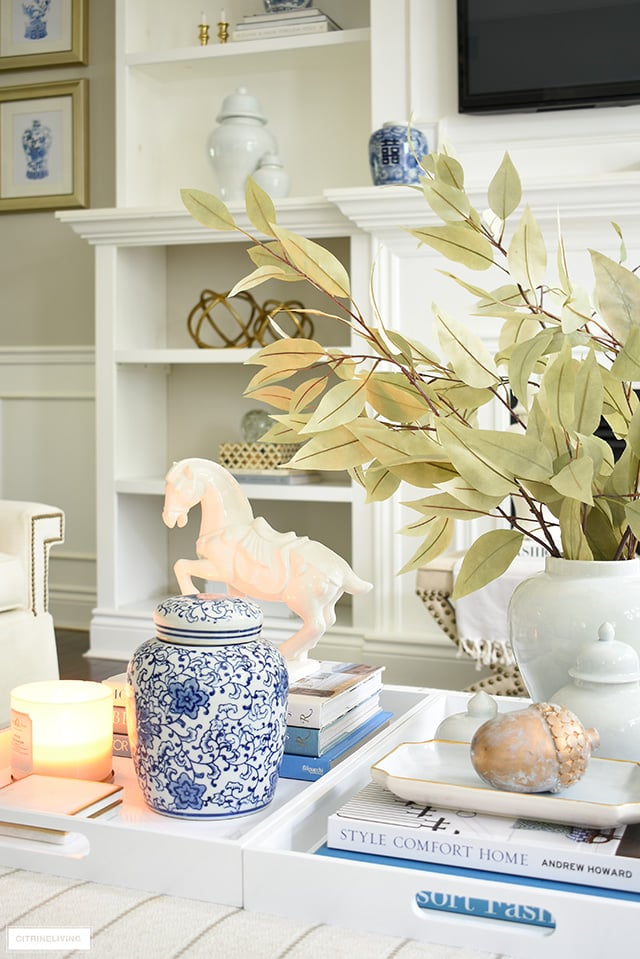 Ottoman/coffee table styled for fall with elegant accessories - ginger jars, scented candle, faux leaves and seasonal accents.