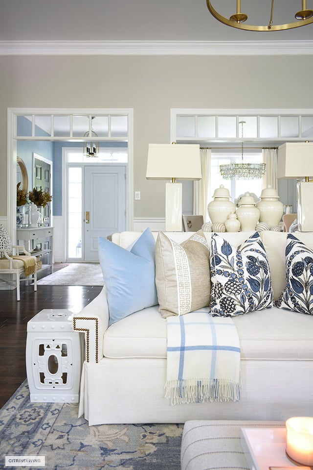 Living room decorated for fall with white sofas and designer pillows, accented with elegant ginger jars.