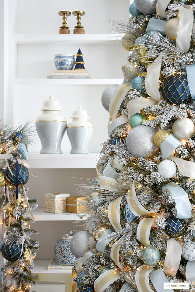Flocked Christmas tree decorated with shades of blue, white, gold and silver. Bookshelves styled with simple decor and a few holiday accessories. 