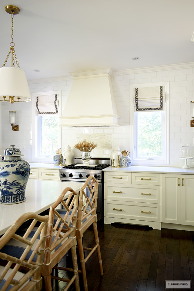 Kitchen with Chinese chippendale barstools, a blue and white ginger jar, and stove decorated for fall with a dried wheat arrangement.